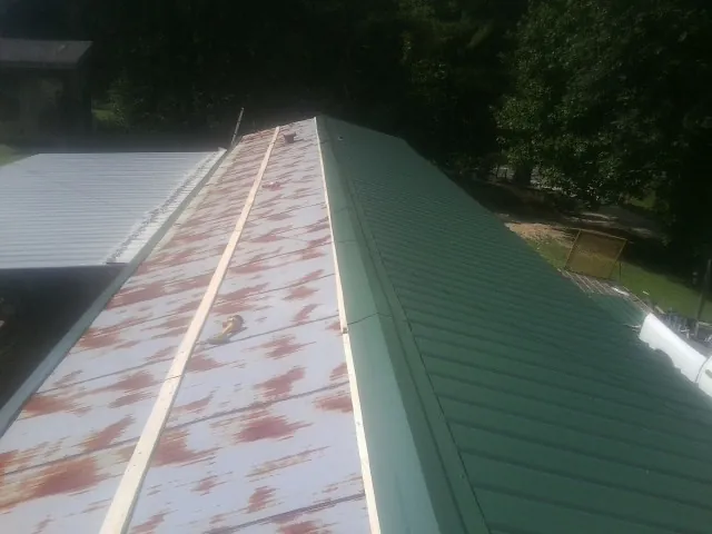 Old rusted panels beside newly installed green metal roofing — Wind Damage Roof Repair by Roofing Brothers in Tannersville