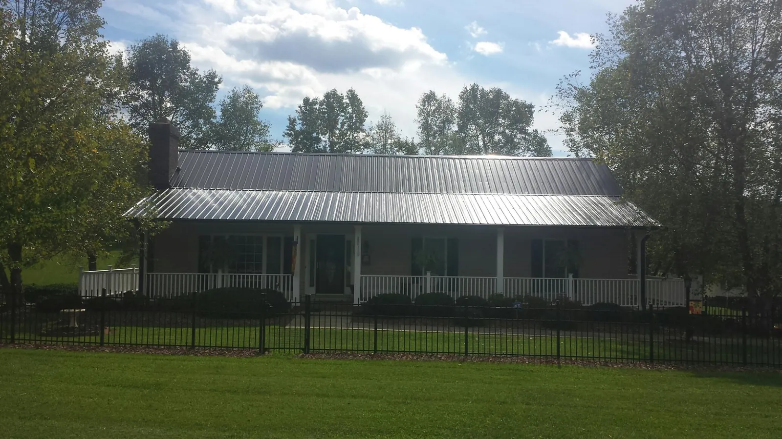 Gray metal roof on a brick ranch with a full width front porch — Gutter Guard Installation work by our crew in Tannersville