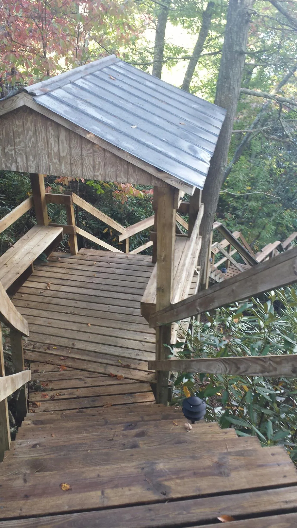 Metal roofed shelter over wooden steps on a wooded walkway — Skylight Repair & Installation work by our crew in Tannersville