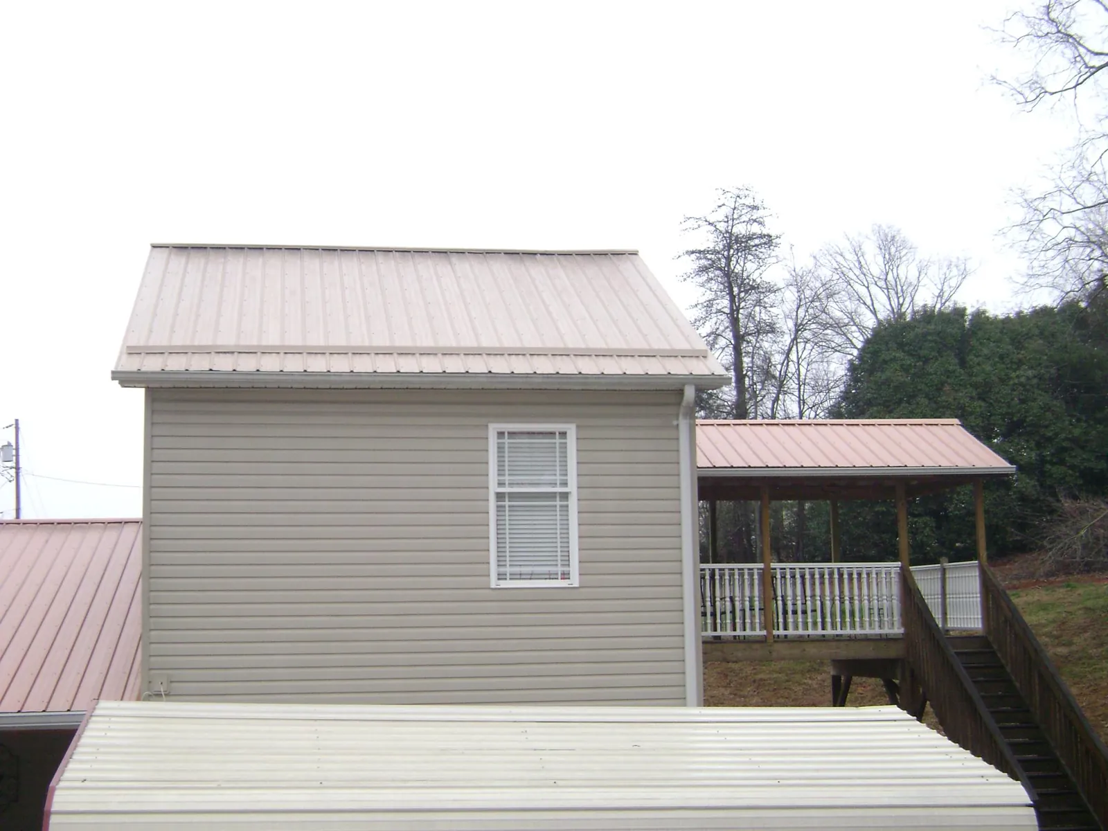 Tan metal roofs on a two story addition and attached porch, from a Roof Replacement job in Tannersville