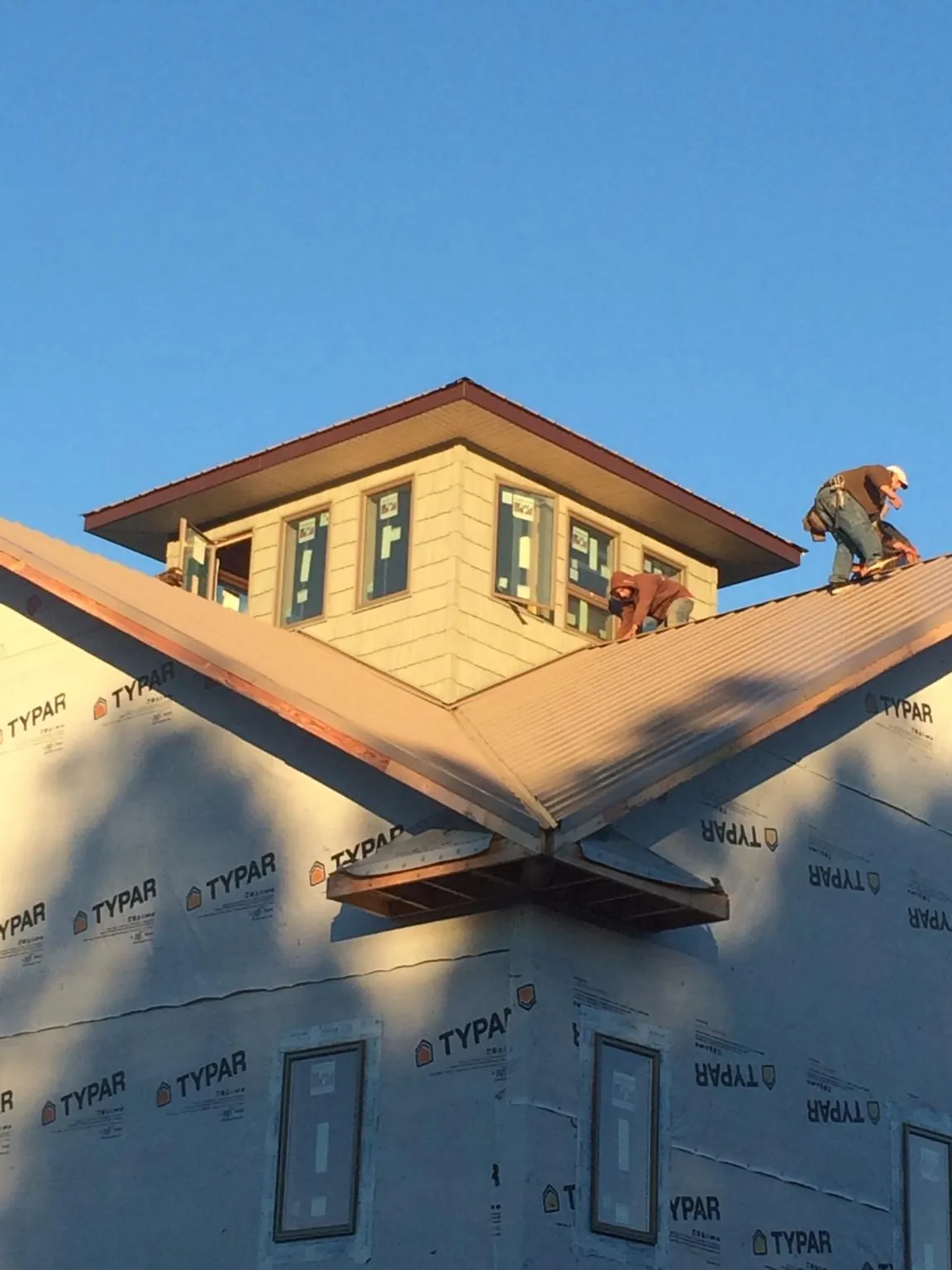 Roofers working around a rooftop cupola on a new metal roof at sunset — Roof Waterproofing in Tannersville by Roofing Brothers